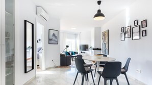 Una cocina moderna con comedor, paredes blancas y un amplio ventanal.