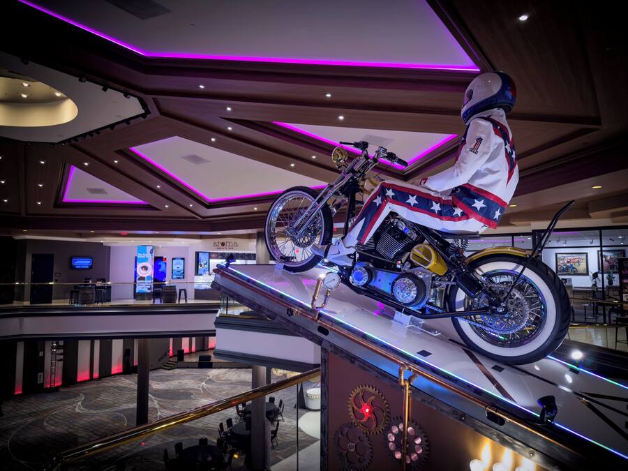 A motorcycle on display in a modern lobby with a high ceiling and ambient lighting.