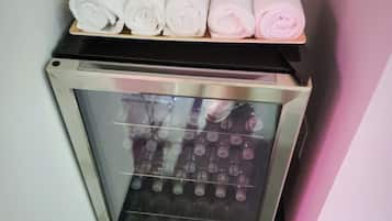 A minibar with bottles of water and neatly rolled towels.