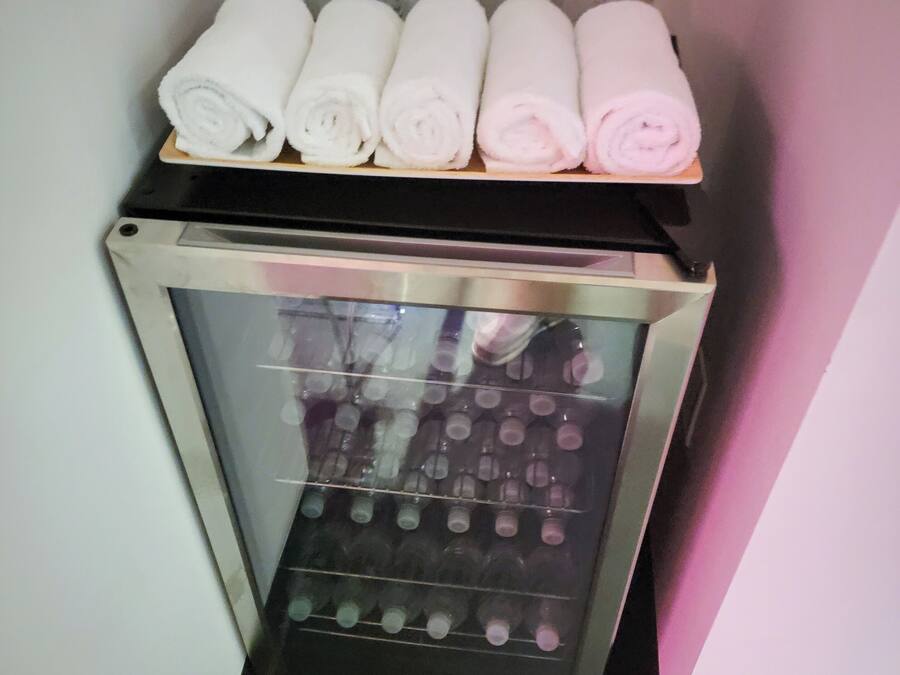 A minibar with bottles of water and neatly rolled towels.