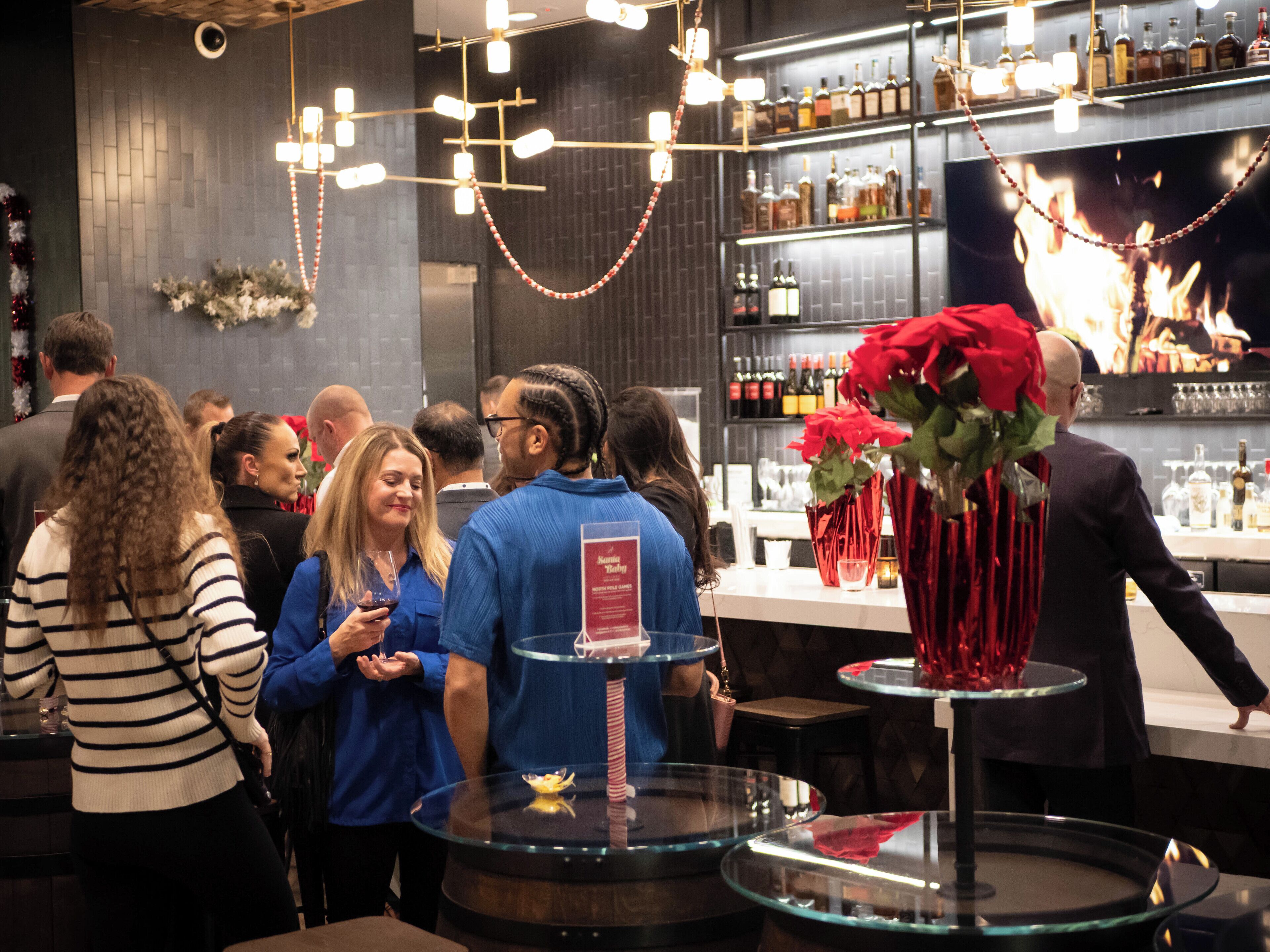 Un espace bar doté d’un intérieur moderne, comprenant un présentoir à vins et une composition florale décorative aux fleurs rouges.
