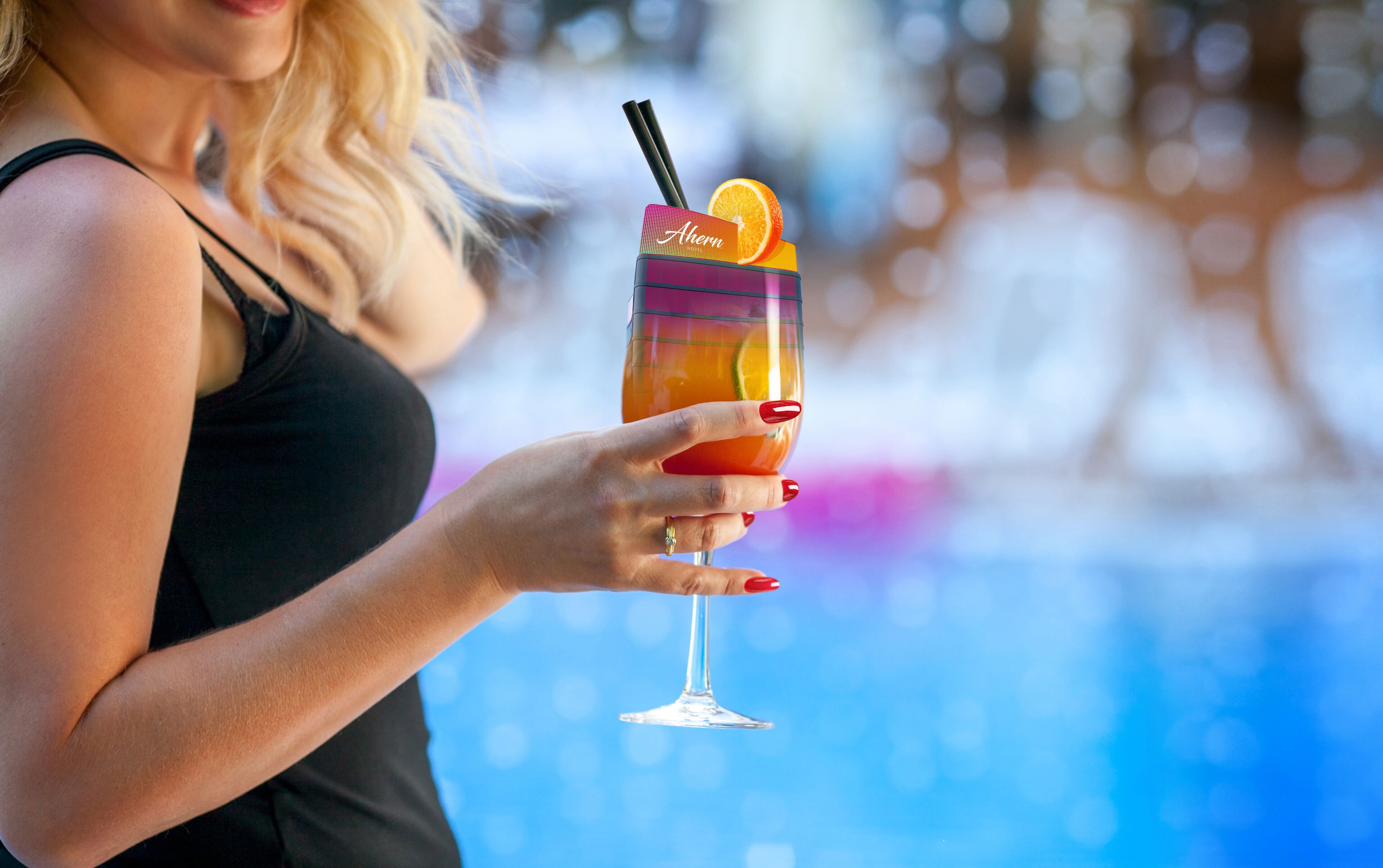 Eine Person hält ein Cocktailglas mit einem Strohhalm und einer Orangenscheibe.