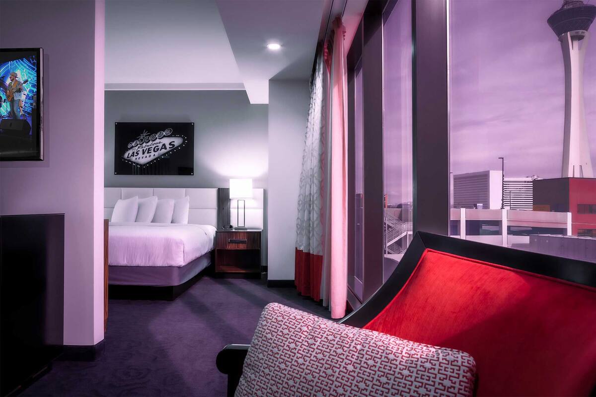 Une chambre d’hôtel avec un lit, une télévision, une pancarte indiquant « Las Vegas » et une vue sur une tour.