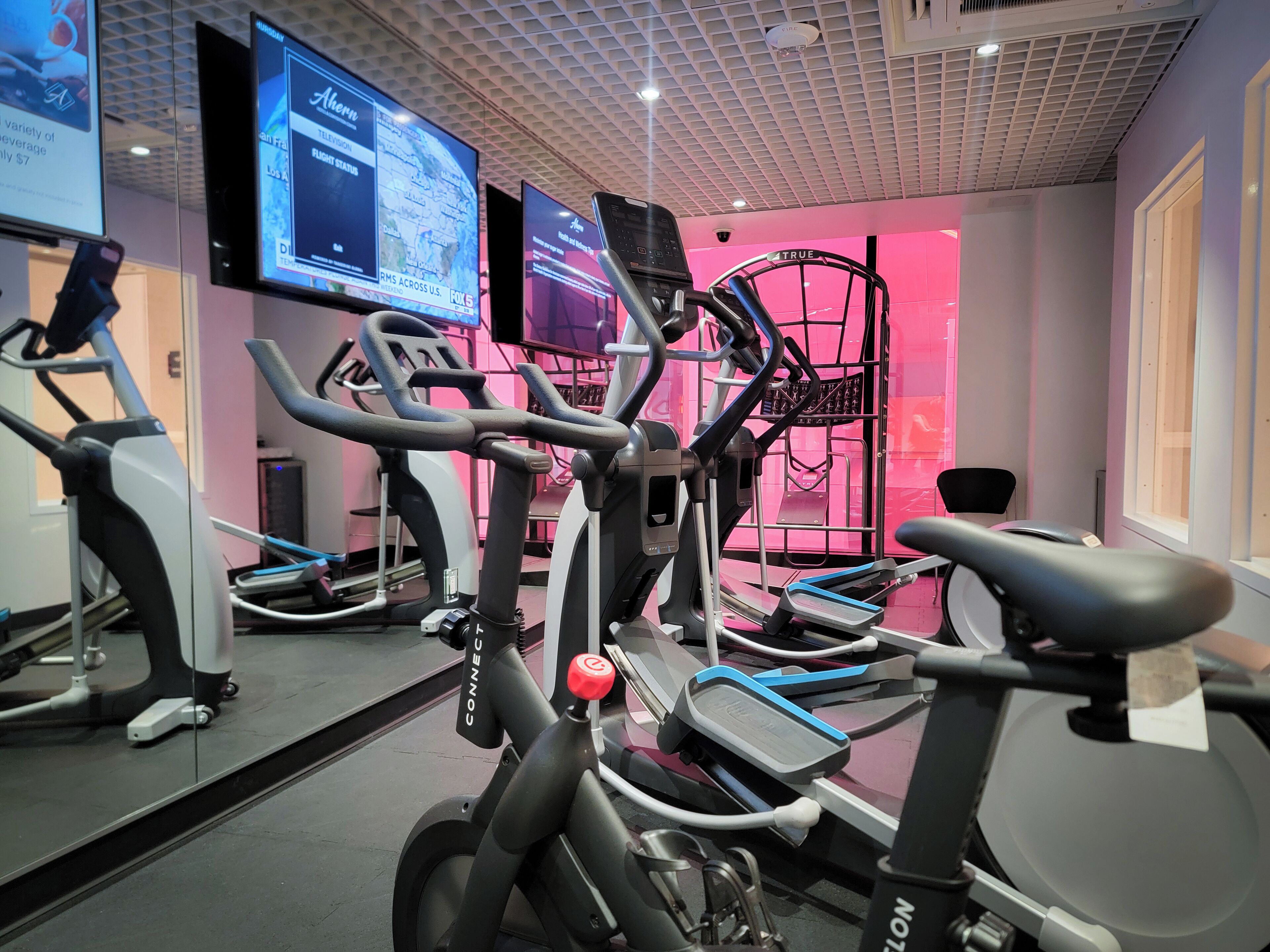 Un gimnasio con varias bicicletas estáticas y un espejo grande.