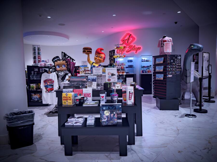 A gift shop with various merchandise displays, including books, toys, and a neon sign.