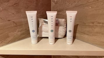 Drie flessen Infuse douchegel, conditioner en shampoo op een plank.