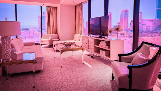 Ein modernes Wohnzimmer mit Blick auf die Stadt, ausgestattet mit einer Couch, Sesseln, einem Couchtisch und einem Fernseher auf einem Schrank.