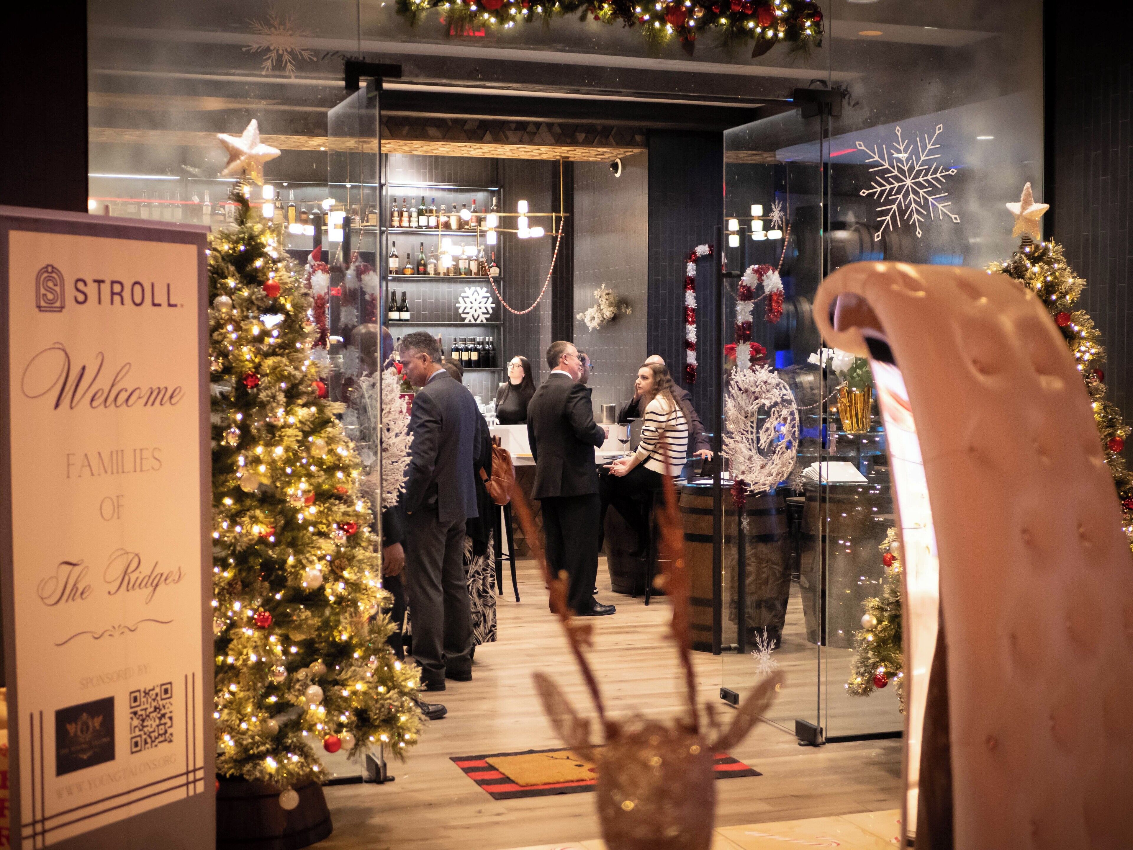 A Christmas event at a hotel with a reception area, decorated Christmas trees, and a sign welcoming families.