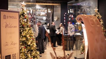 A Christmas event at a hotel with a reception area, decorated Christmas trees, and a sign welcoming families.