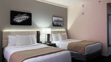 A hotel room with two beds, a nightstand with a lamp, a phone, and a framed picture on the wall.