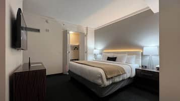 A hotel room with a bed, bedside tables, a TV, and a walk-in closet.