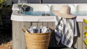 A hot tub with glasses and a hat, a striped towel, and a wicker basket. - Wine Country Escape, Heated Pool + Hot Tub Near Wineries (Santa Rosa)