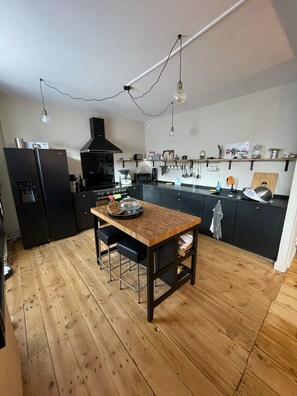 Une cuisine moderne avec une table en bois, des meubles de rangement noirs et un réfrigérateur noir.