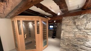 Een houten kast met glazen deuren, een stenen muur en een plafond met zichtbare balken.