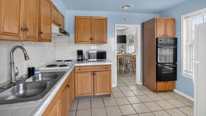 Una cocina con armarios de madera, un lavamanos de acero inoxidable, una estufa, un microondas y un refrigerador.