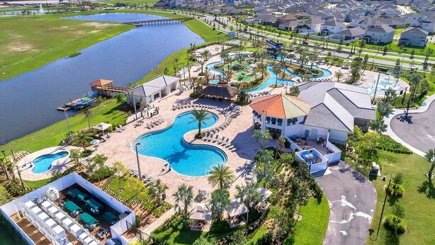 An aerial view of a resort with multiple swimming pools, a dock, and a residential area with houses. - Private Pool, Premium Resort Amenities Included (Kissimmee)