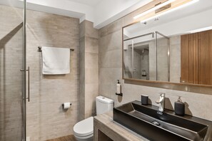 Features a sleek sink, large mirror, and glass-enclosed shower area.