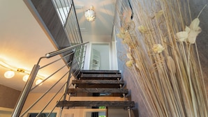 Eine moderne Treppe mit Metallgeländer, eine Wand mit getrockneten Pflanzen und eine Chandelier.