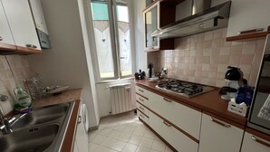 Una cocina con estufa a gas, un lavamanos, armarios y una ventana con persianas.