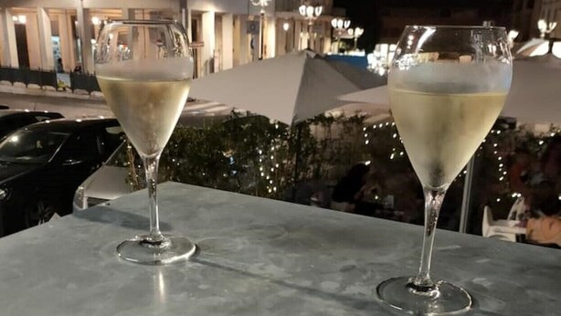 Dos copas de champán sobre una mesa, con un paisaje urbano al fondo.
