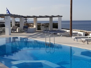 A pool area with lounge chairs and a pergola overlooking the sea. - Sea paradise villas (Santorini)