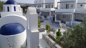 A white building with a blue dome and a stone pillar. - Sea paradise villas (Santorini)