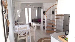 A modern kitchen with white cabinetry and a wooden staircase. - Sea paradise villas (Santorini)