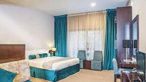 A hotel room with a bed, two armchairs, a desk with a computer, and a TV. - Signature Hotel Dubai Marina (Gillingham)