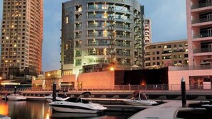 A waterfront hotel with a curved facade, multiple balconies, and a marina with boats. - Signature Hotel Dubai Marina (Gillingham)
