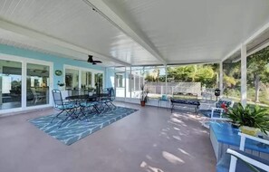 A covered patio area with a dining table and chairs, a seating area with a bench, and a view of the backyard. - Beautiful Florida Home 3 Miles to Venice Beach (Venice)
