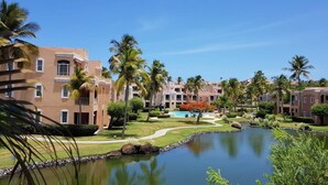 A resort with multiple buildings, a central pool, and surrounding palm trees. - Escape Beach Studio, Fairway Courts, Palmas del Mar (Humacao)