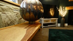 Una habitación con una mesa de madera, un objeto metálico esférico, un armario blanco y un florero con luces.