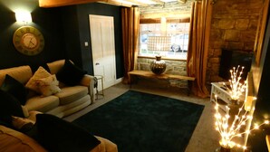 Una sala de estar acogedora con un sofá, una alfombra, una chimenea de piedra y una ventana con cortinas.