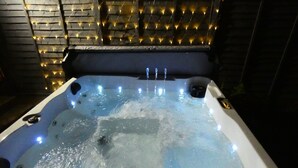 Un jacuzzi con chorros de agua, rodeado de muros de piedra y luces colgantes.