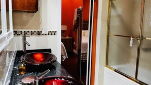 Ein modernes Badezimmer mit einem großen Spiegel, einem Waschbecken mit roter Schüssel und einer Duschkabine aus Glas.