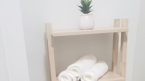 Ein Holzregal mit gerollten weißen Handtüchern und einem kleinen Topfpflanzen.