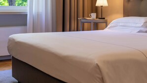 A neatly made bed with a headboard, a bedside table with a lamp, and a window with curtains. - Villaggio Narrante - Foresteria Delle Vigne (Serralunga d'Alba)