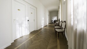 A hallway with wooden flooring, white walls, and a dining area with chairs and a table in the distance. - Villaggio Narrante - Foresteria Delle Vigne (Serralunga d'Alba)