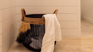 A corner of a room with a woven basket, a white towel, and a black-framed mirror on the wall. - 4 Bedroom WOW w/heated floors, Ski out access to Snowbird and steam bath. (Alta)