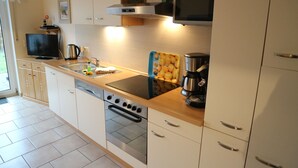 A modern kitchen with a stove, oven, microwave, and a coffee maker. - Vacation home "Sömmerwind 2 " Norddeich (Norden)