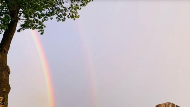 Un foyer avec des bûches, une chaise en bois et un arc-en-ciel en arrière-plan.