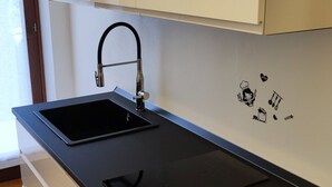 A modern kitchen with white cabinets, a black countertop, and a built-in stove. - Gardaland House (Ronchi)