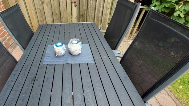 A black metal table with two cans on a mat, surrounded by mesh screens. - Vacation home "Sömmerwind 4" Norddeich, Riedeweg 12 (Norden)
