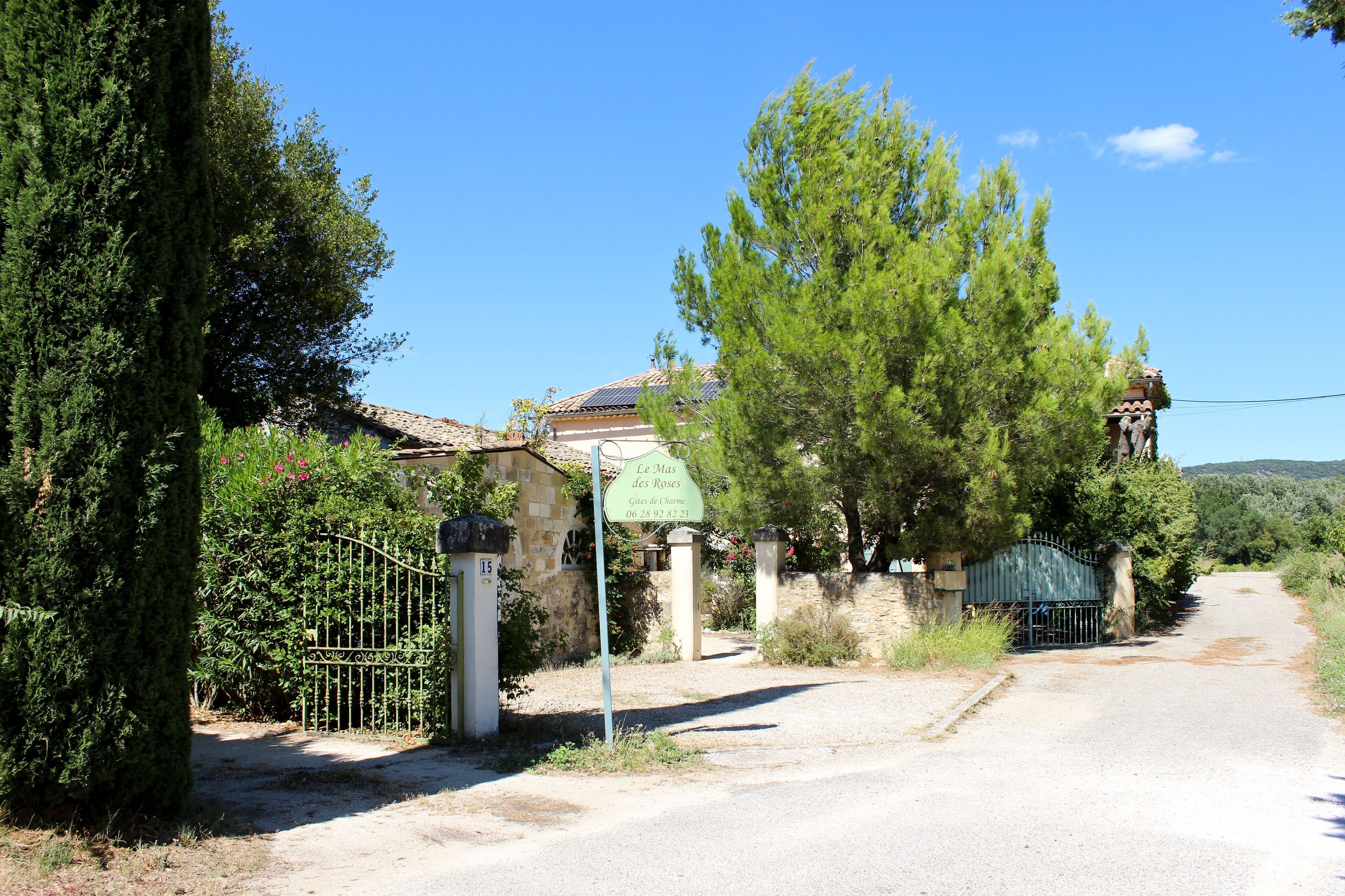 Uma estrada rural leva a um edifício de pedra com uma placa que diz "Le Mas des Roses".