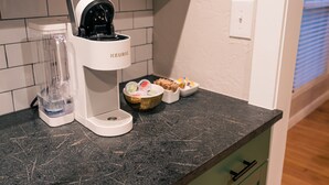 Una encimera de cocina con una cafetera, una licuadora y un recipiente pequeño con alimentos.