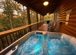 Un bain à remous sur une terrasse en bois, avec vue sur les arbres.