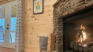 Ein Holzinnenraum mit Kamin aus Stein, einem gerahmten Bild und einer Tür mit Blick.