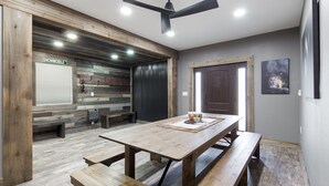 A dining area with a wooden table and benches, a ceiling fan, and a wall-mounted coat rack. - Pet Friendly Home! Cub House,3Br/2½Ba,Sleeps 8,Firepit,BBQ,Golf,20m 2 YNP (Island Park)