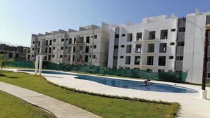 A modern building with multiple floors and balconies, a swimming pool, and a well-maintained lawn. - Rent New Apartment in Acapulco 5 min. from the airport beach and La Isla. (Acapulco de Juárez)