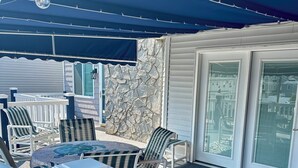 An outdoor patio area with a table and chairs, a stone wall, and a covered seating area.